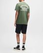 Hombre con Camiseta Deus Venice Address Verde Pino espalda